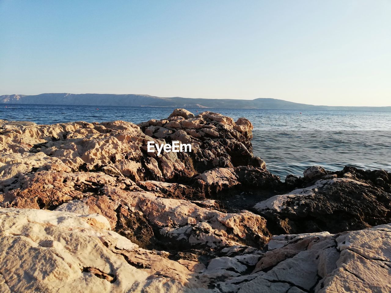 SCENIC VIEW OF ROCKY BEACH AGAINST CLEAR SKY