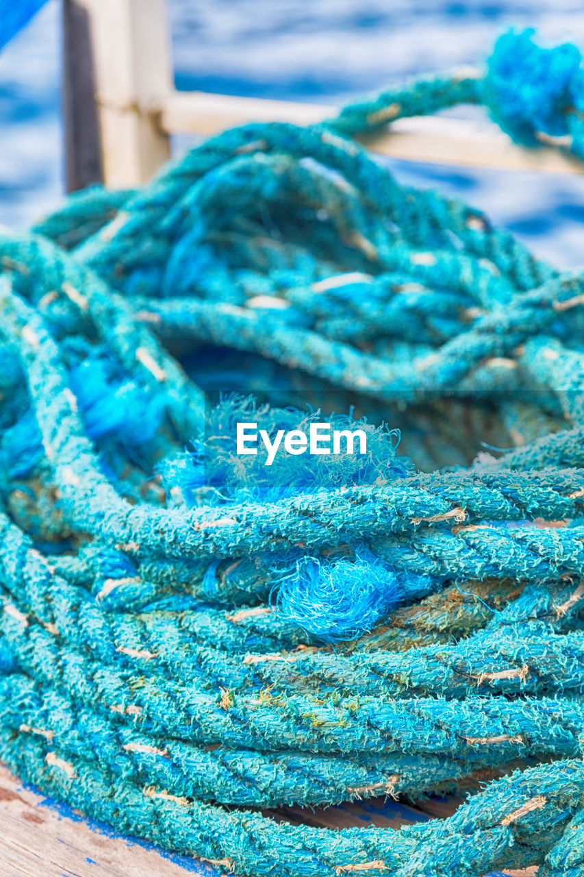 CLOSE-UP OF FISHING NET AT BLUE WATER