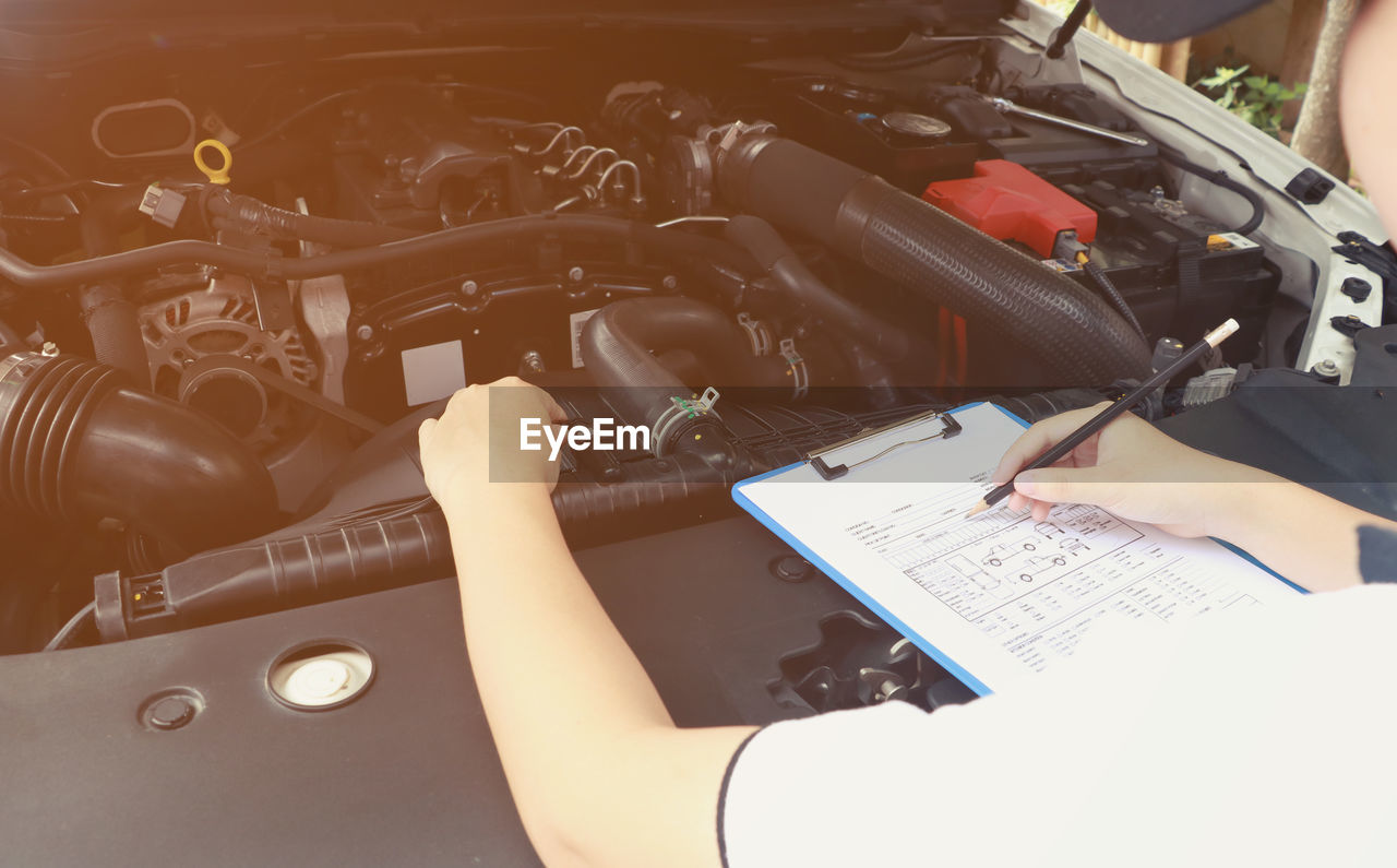 High angle view of mechanic writing in paper at auto repair shop