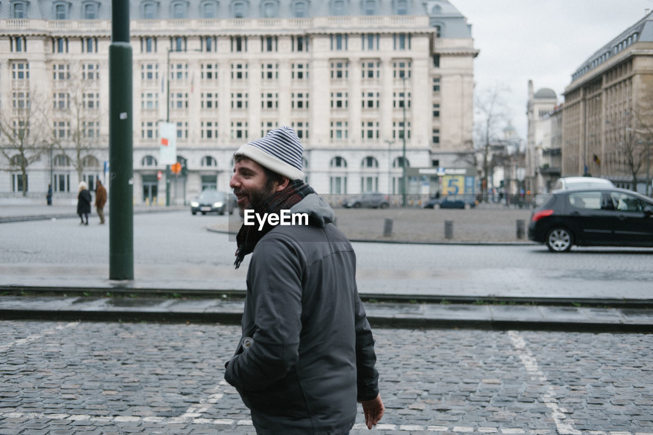 FULL LENGTH PORTRAIT OF MAN STANDING ON CITY STREET