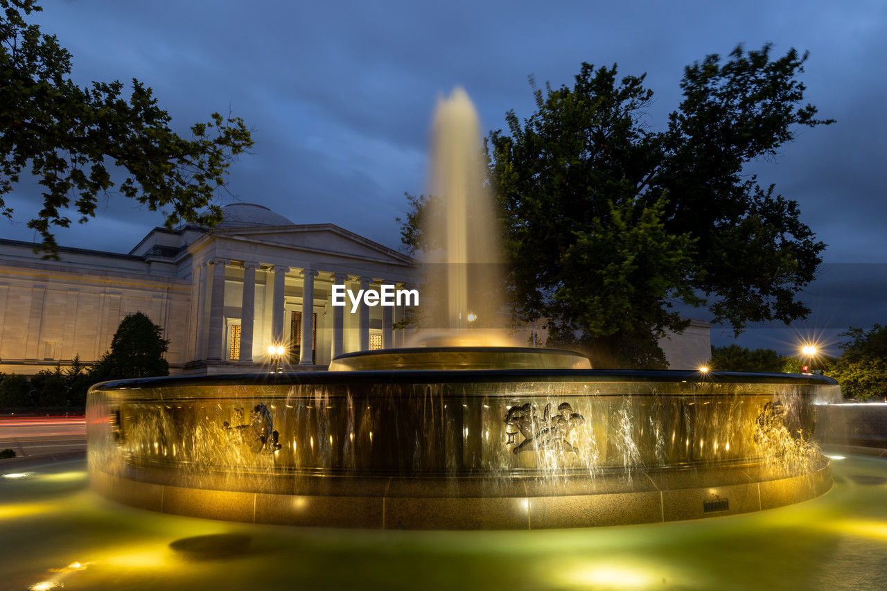 Andrew mellon memorial fountain at dusk with the national gallery of art in the background