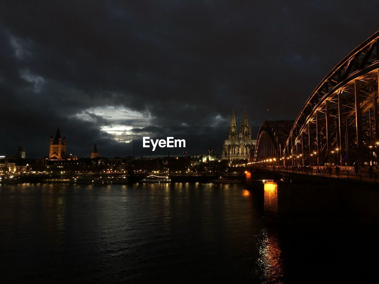 VIEW OF ILLUMINATED BRIDGE OVER RIVER AGAINST SKY