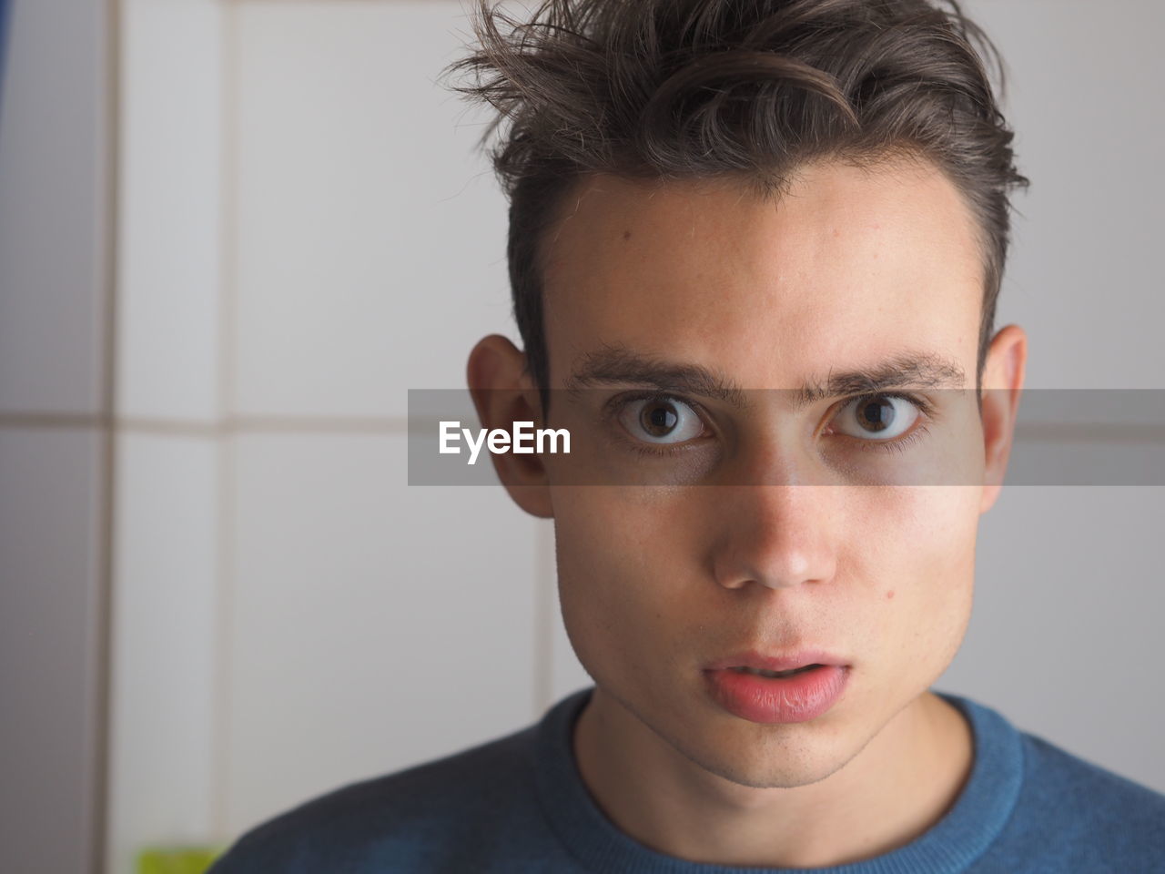 Close-up portrait of shocked young man at home