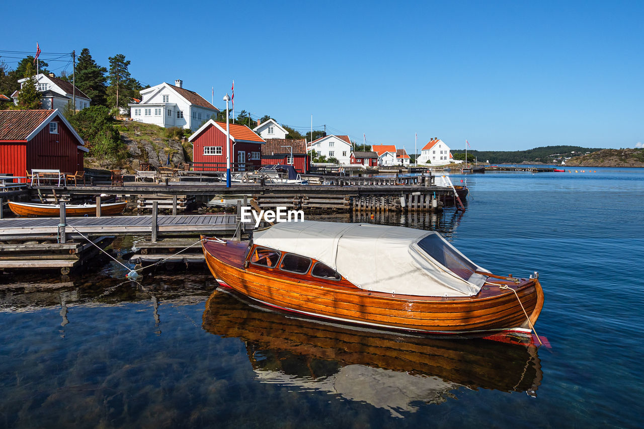 BOAT MOORED IN LAKE AGAINST BUILDINGS