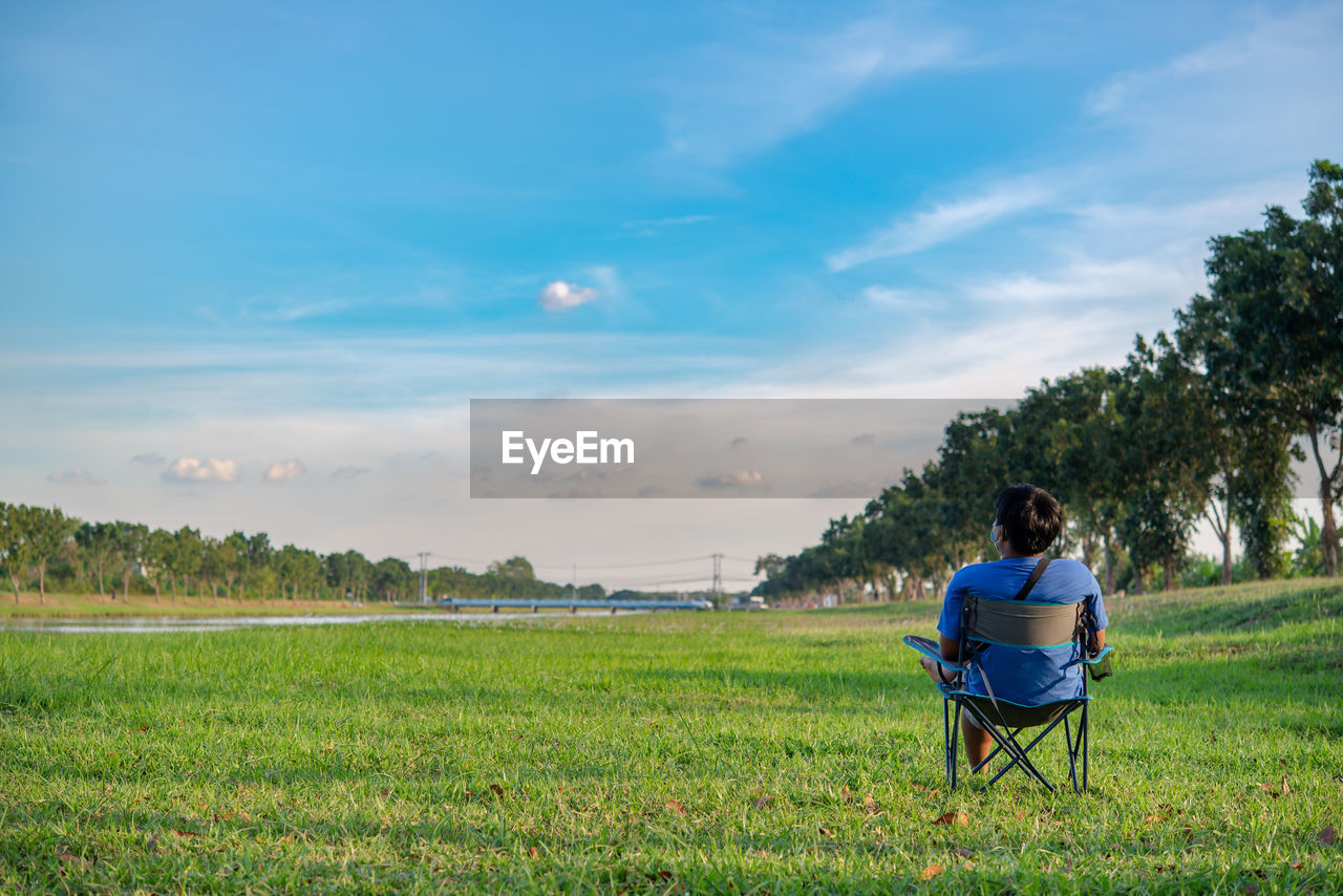 REAR VIEW OF COUPLE SITTING ON FIELD