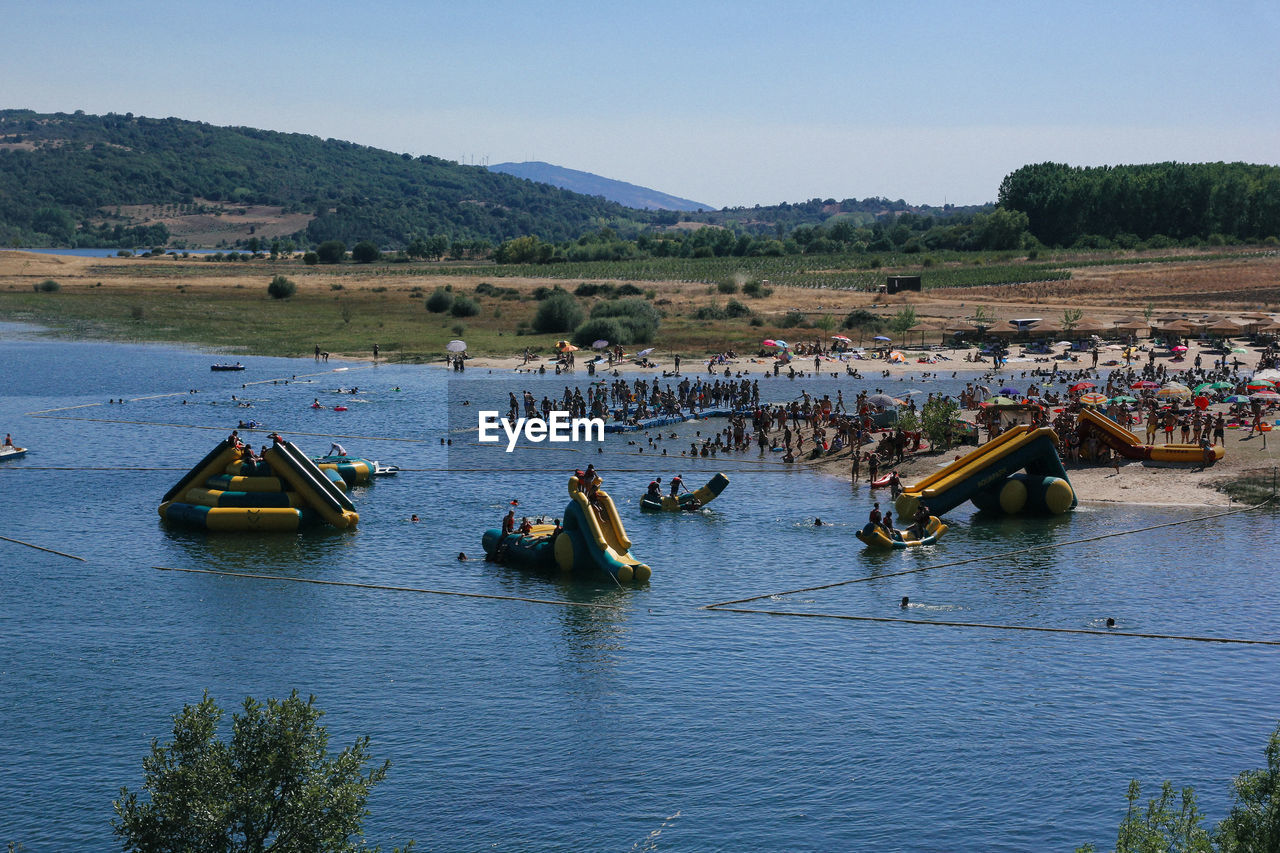 HIGH ANGLE VIEW OF PEOPLE ON RIVERBANK AGAINST SKY