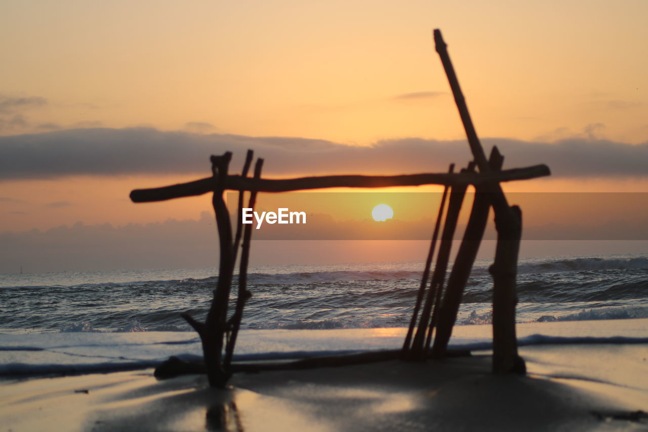 Silhouette tree on beach against sky during sunset