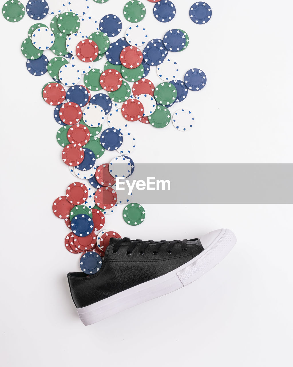 High angle view of shoe with gambling chips on white background