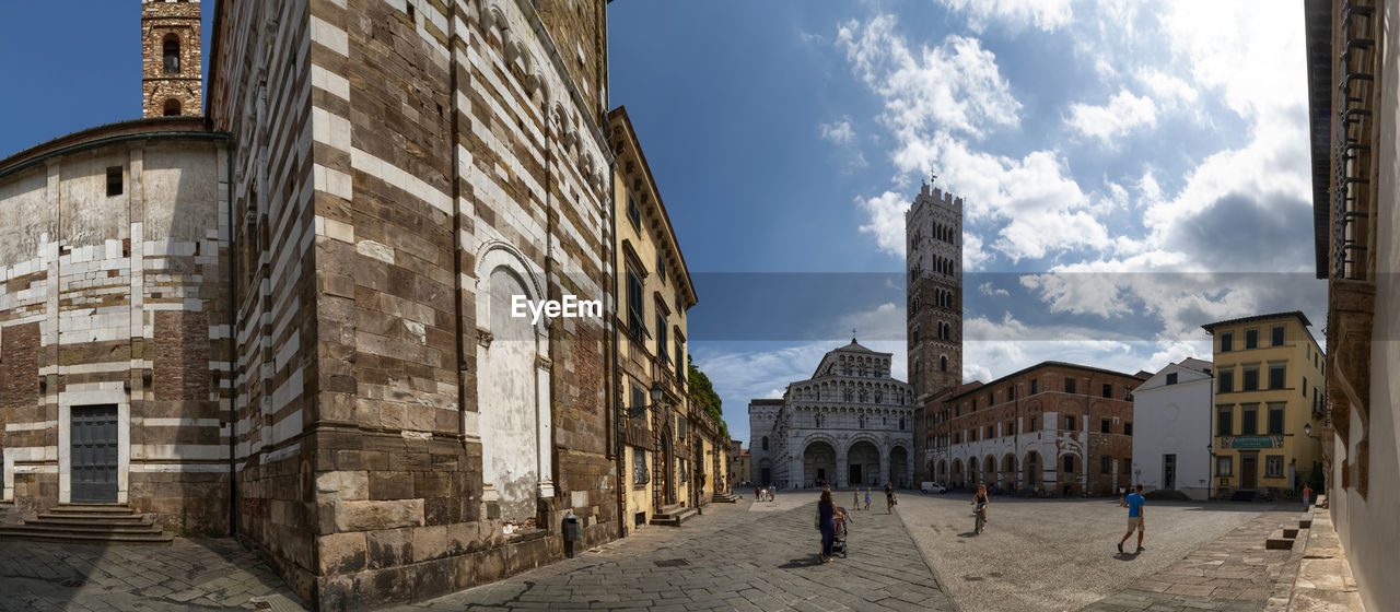 Lucca, Tuscany, Italy. August 2020. Amazing view of the cathedral square of San Martino. Large format panoramic photo. Beautiful summer day, people in the square. Arch Architecture Bell Bell Tower BIG Building Cathedral Catholic Church City Columns Duomo Europe Exterior Façade Famous Format Gothic Historic Italia Italy Landmark Large Lifestyle Lucca Lucca Cathedral Martin Martino Medieval Monument Old Outdoors Panoramic People Religion Religious  Romanesque San San Martino Sky