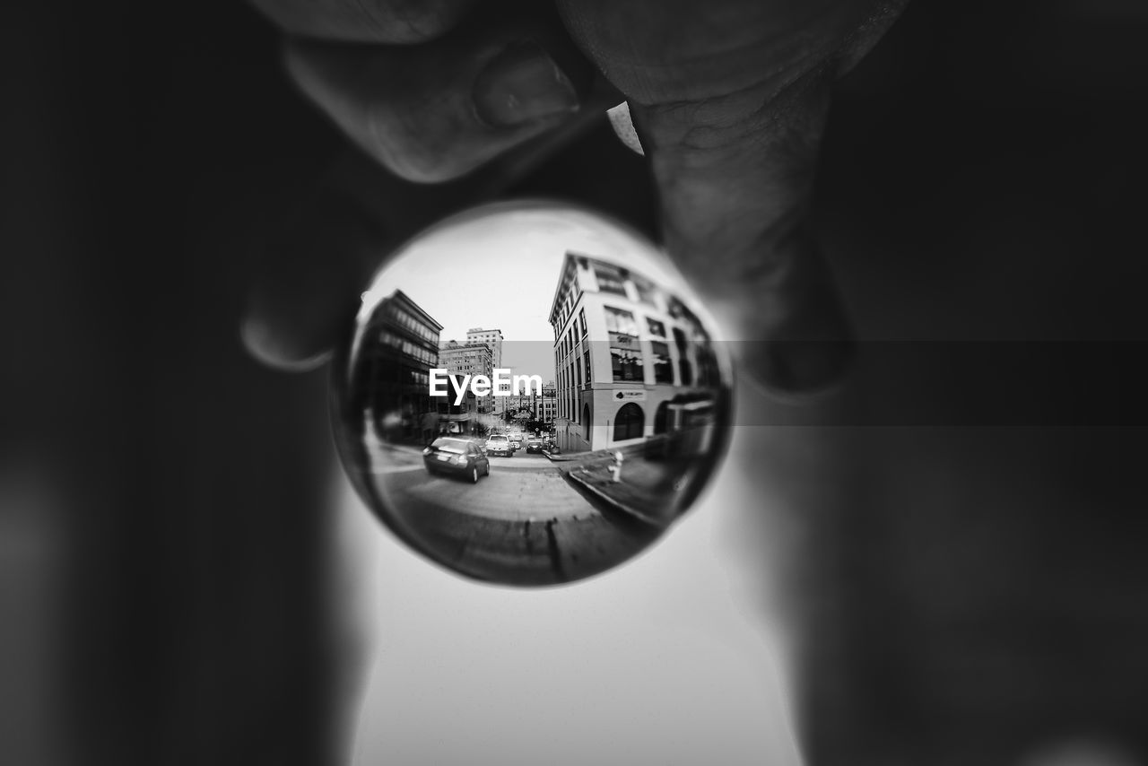 CLOSE-UP OF HAND HOLDING GLASS WITH REFLECTION OF LIGHT