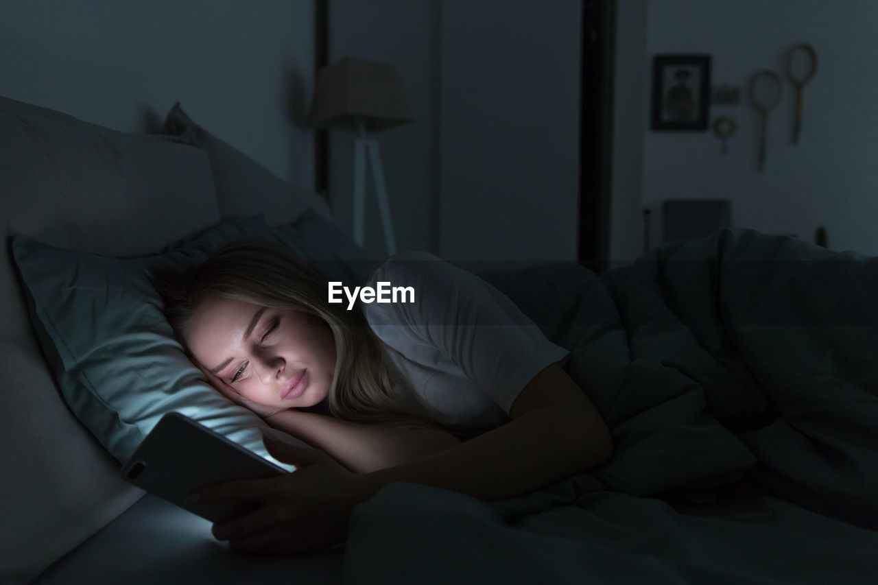 Woman using smart phone while lying on bed