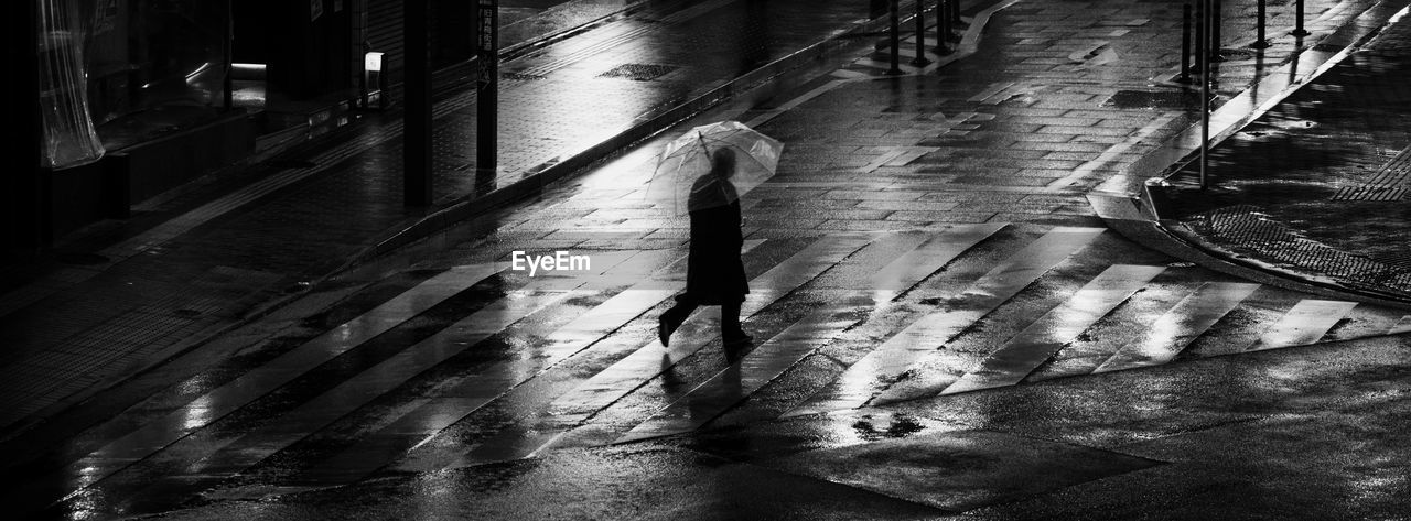 High angle view of man walking on wet street in city