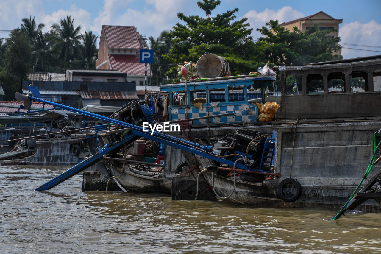 BOAT MOORED IN RIVER AGAINST BUILDINGS