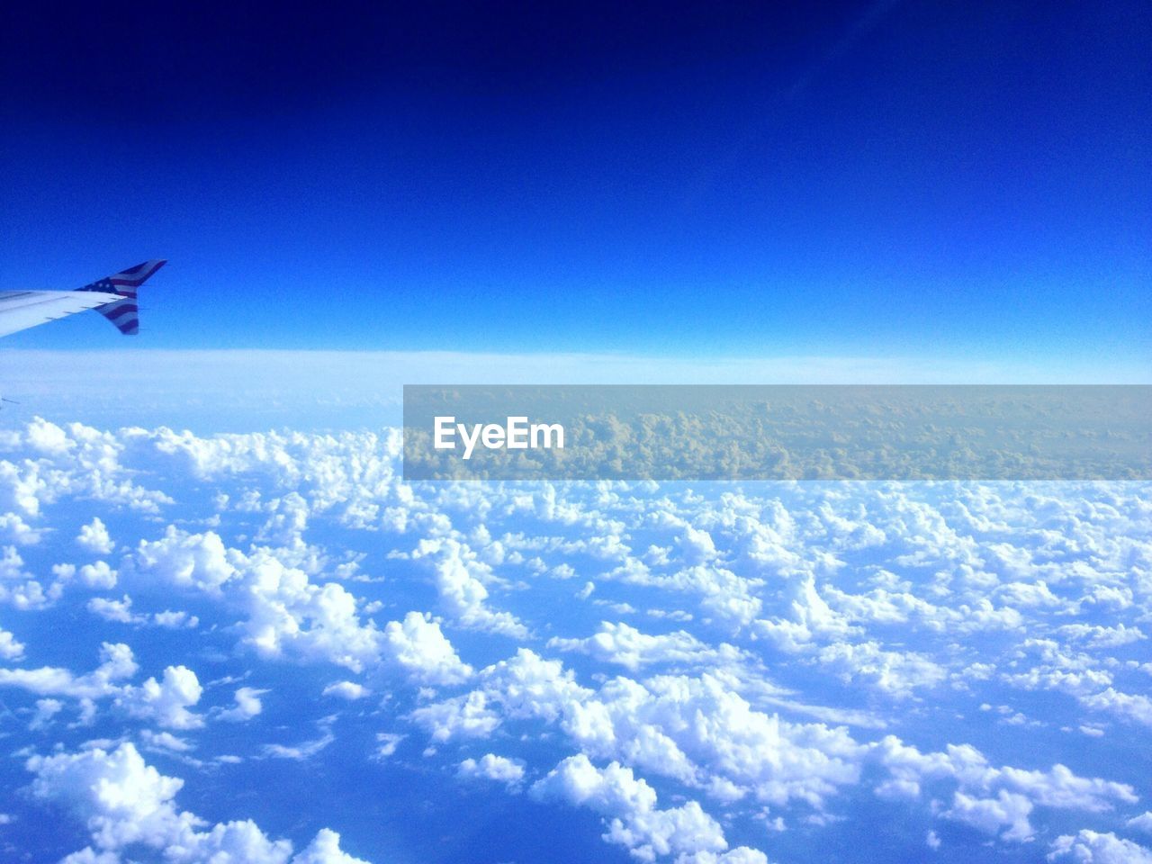 CROPPED IMAGE OF AIRPLANE FLYING OVER CLOUDSCAPE