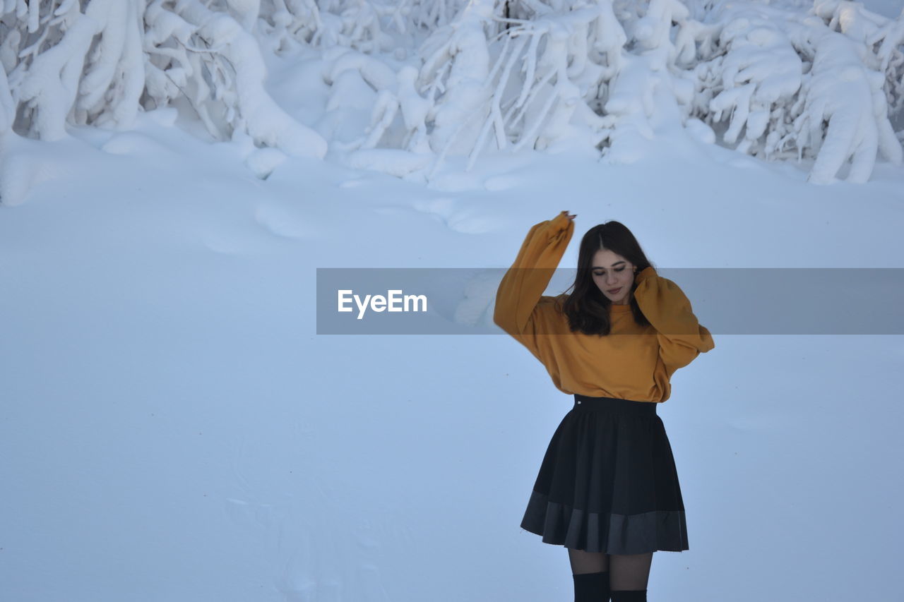 Fashionable teenage girl standing in snow