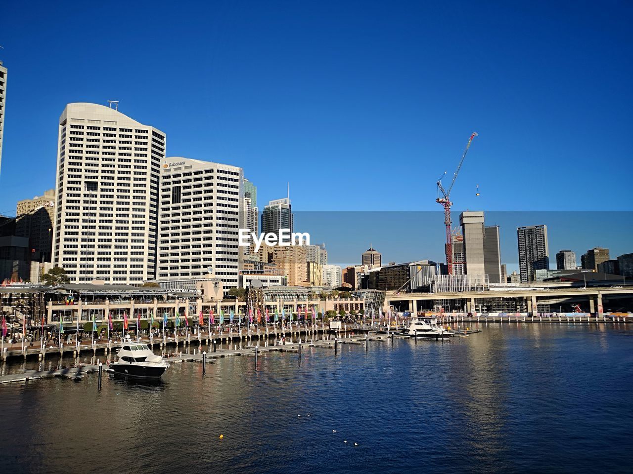 River by buildings in city against clear blue sky