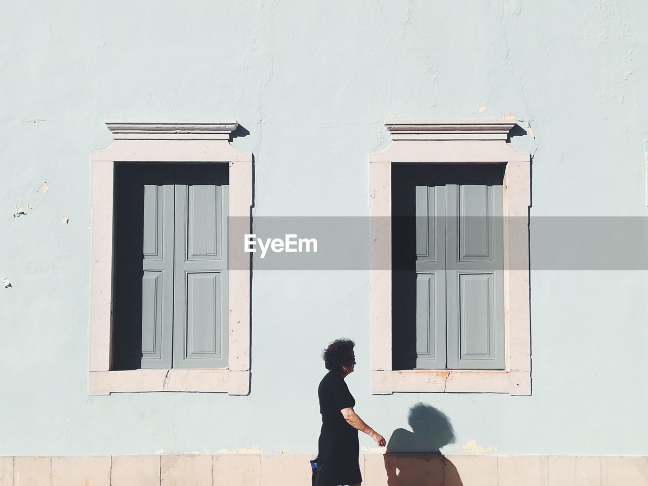 REAR VIEW OF GIRL STANDING BY WINDOW