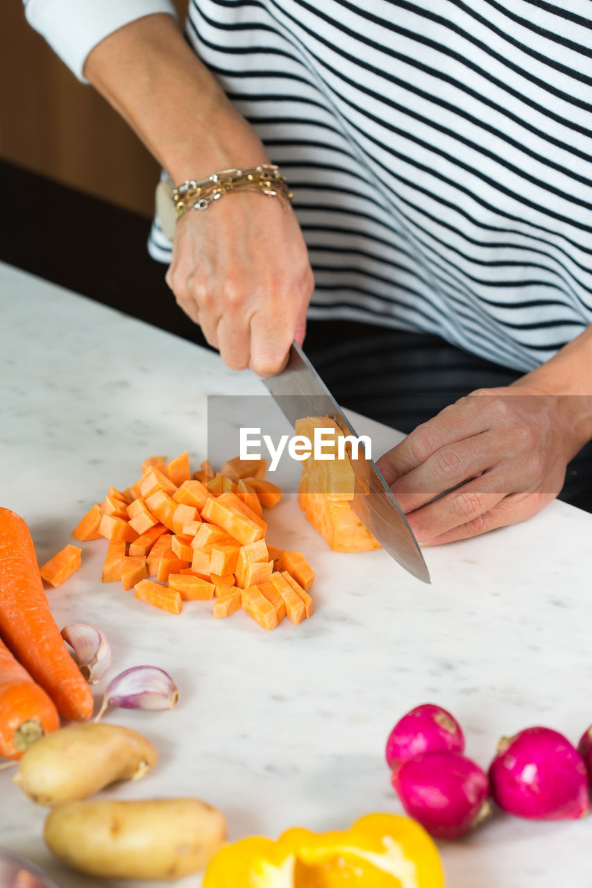 Woman slicing vegetables while cooking stew. close up of woman hands cutting vegetables