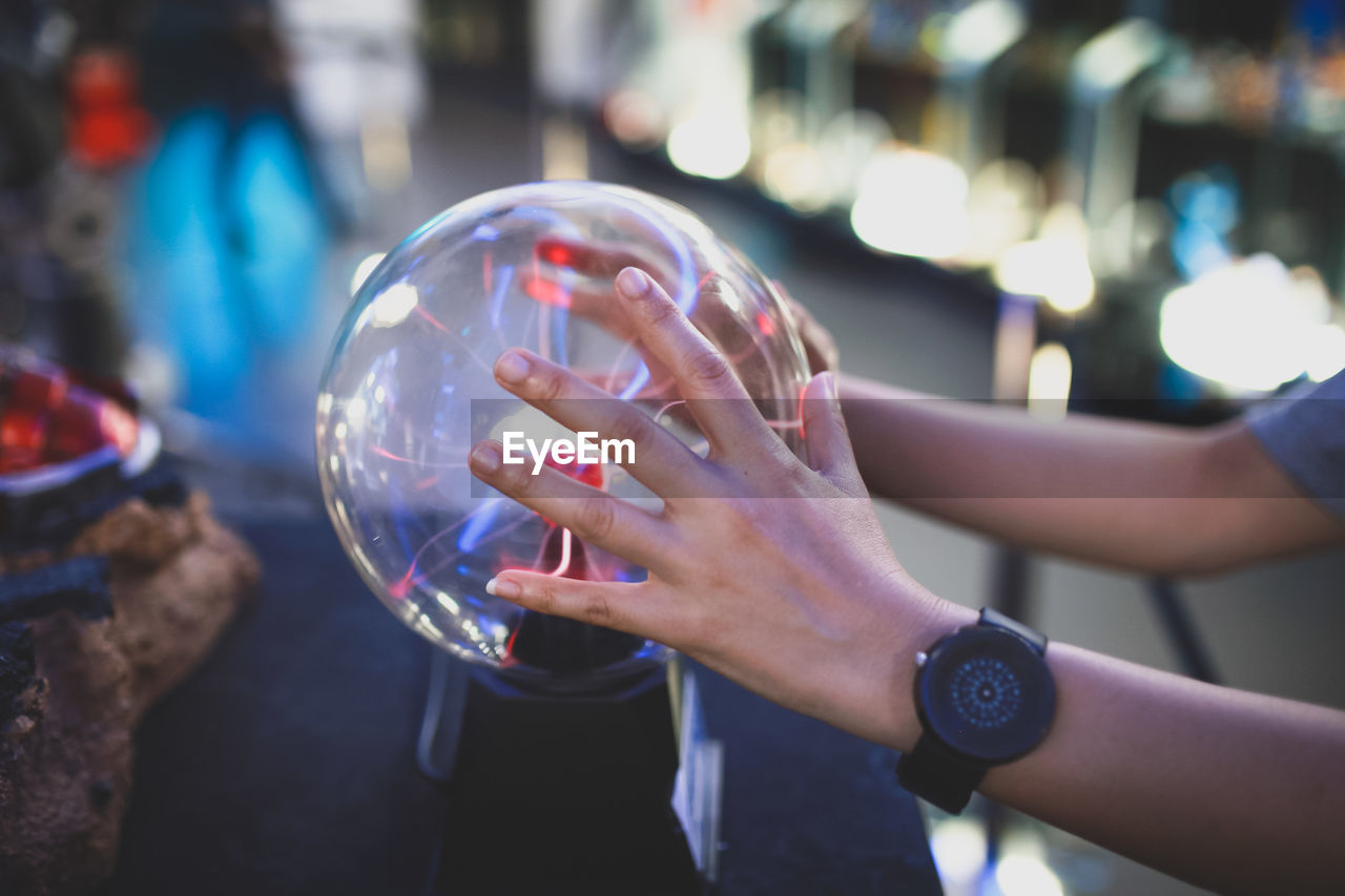 CROPPED IMAGE OF HAND HOLDING CRYSTAL BALL WITH REFLECTION