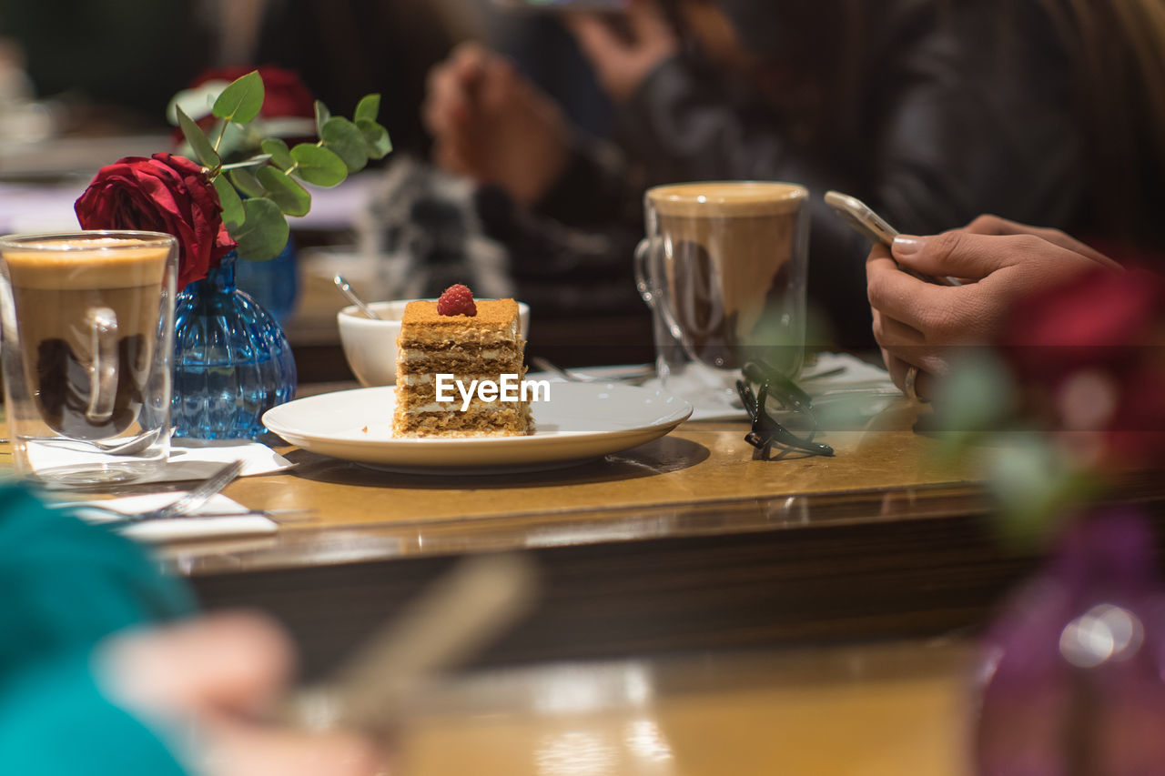 Cropped hands of woman using phone at restaurant