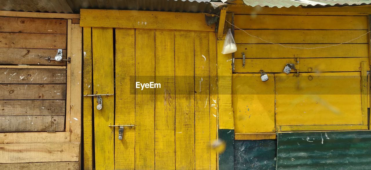 FULL FRAME SHOT OF YELLOW METAL DOOR WITH CLOSED DOORS