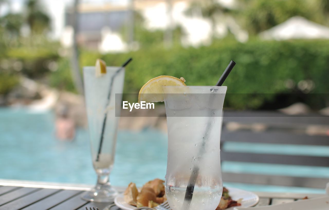 Close-up of drink on table against swimming pool