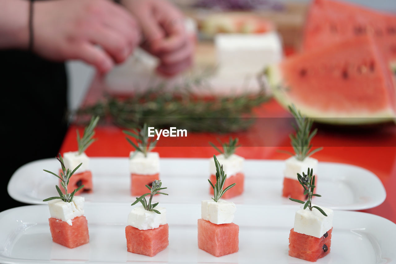 Close-up of watermelon and feta cheese cubes with rosemary on cutting board