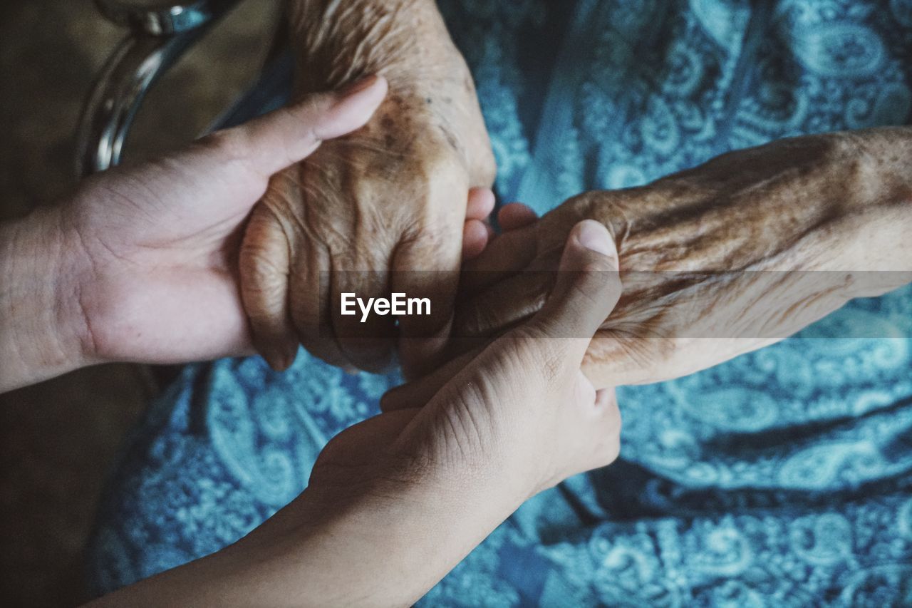 Cropped image of person holding senior woman hands