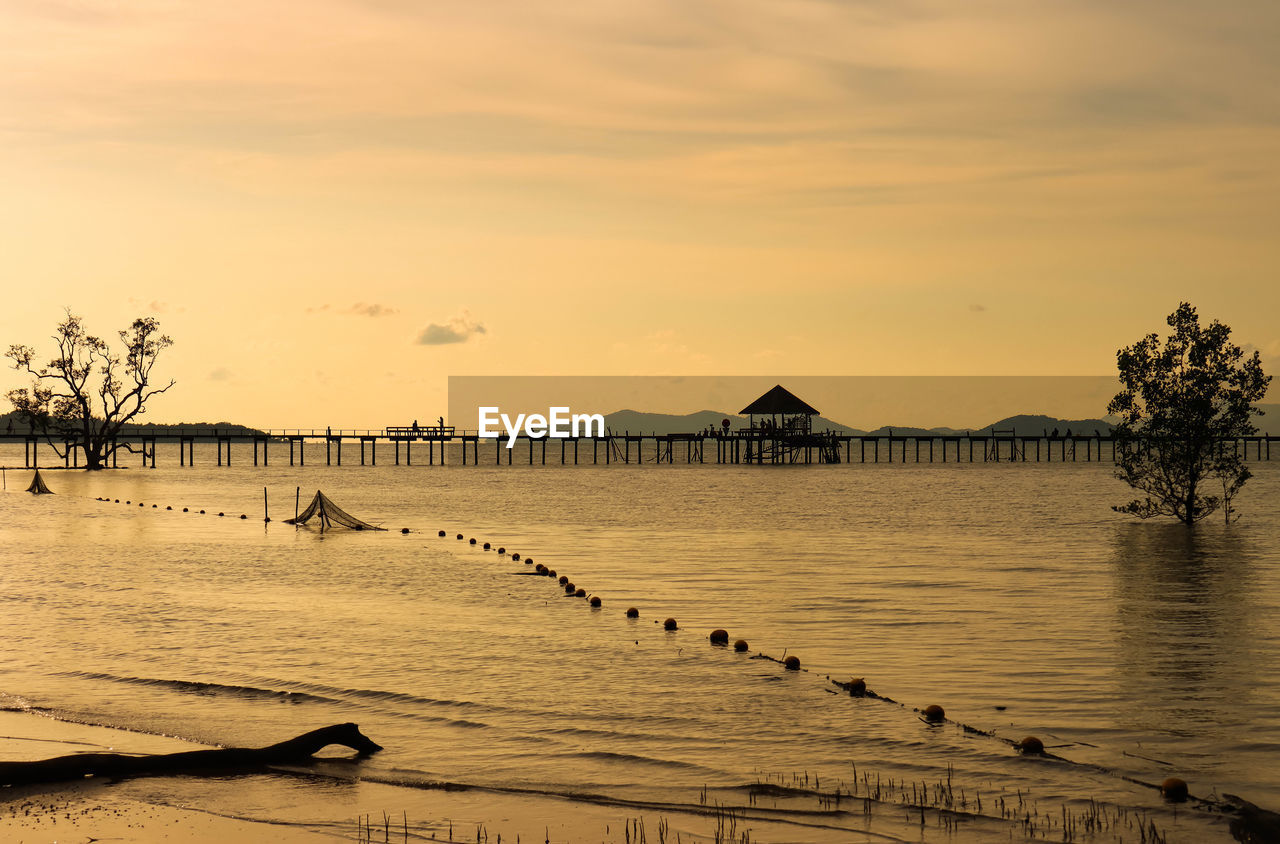 Sunsetting over the wooden bridge at the calm sea