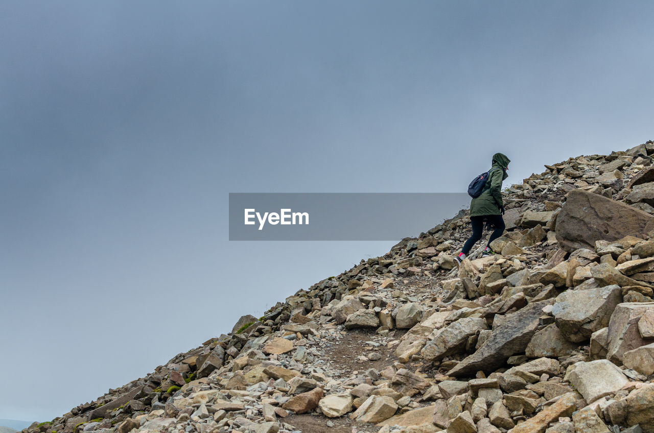 Female hiker climbing the screes and rockfall at scafell pike in the lake district, cumbria