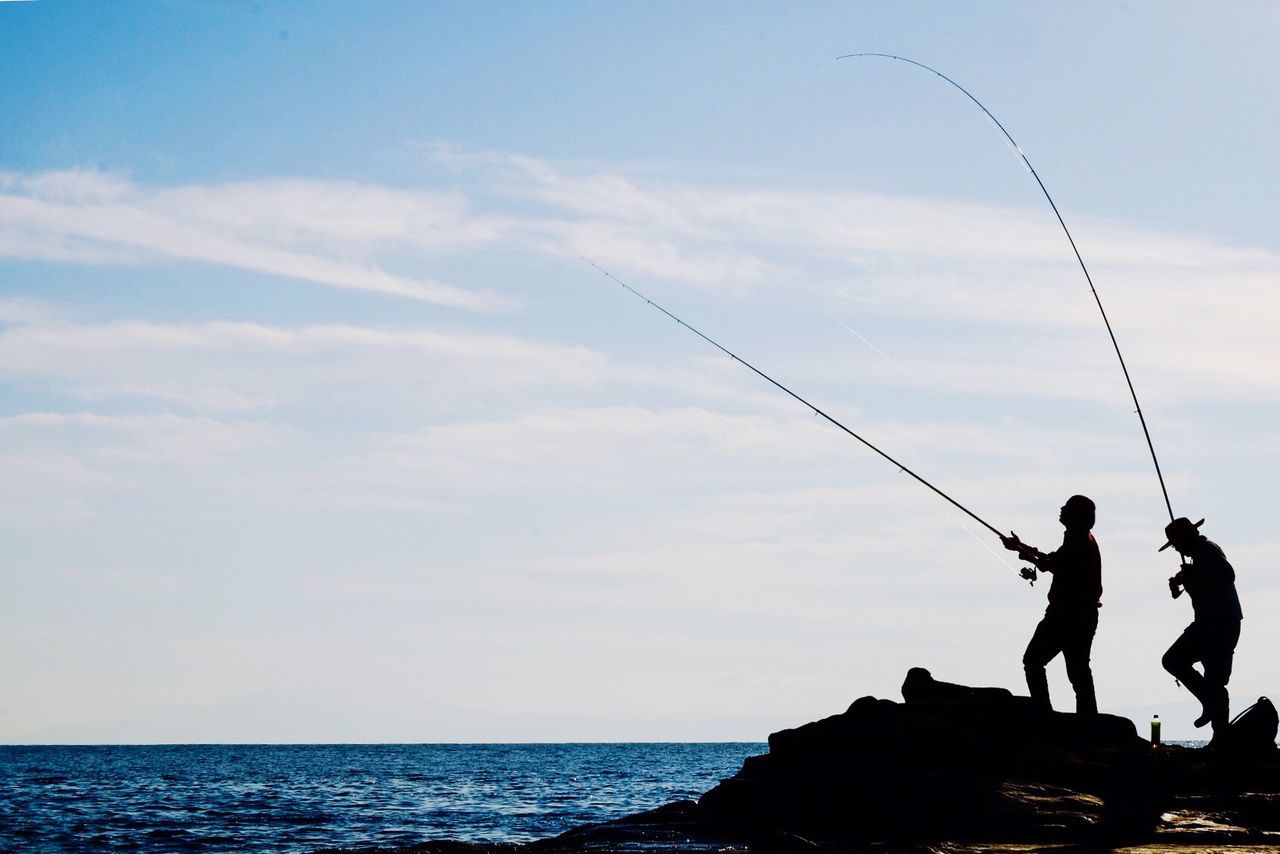 MAN FISHING IN SEA AGAINST SKY