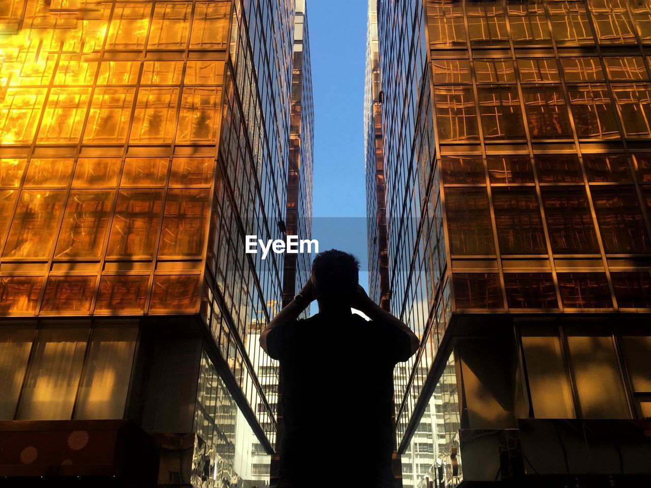 Man standing in front of glass buildings during sunset