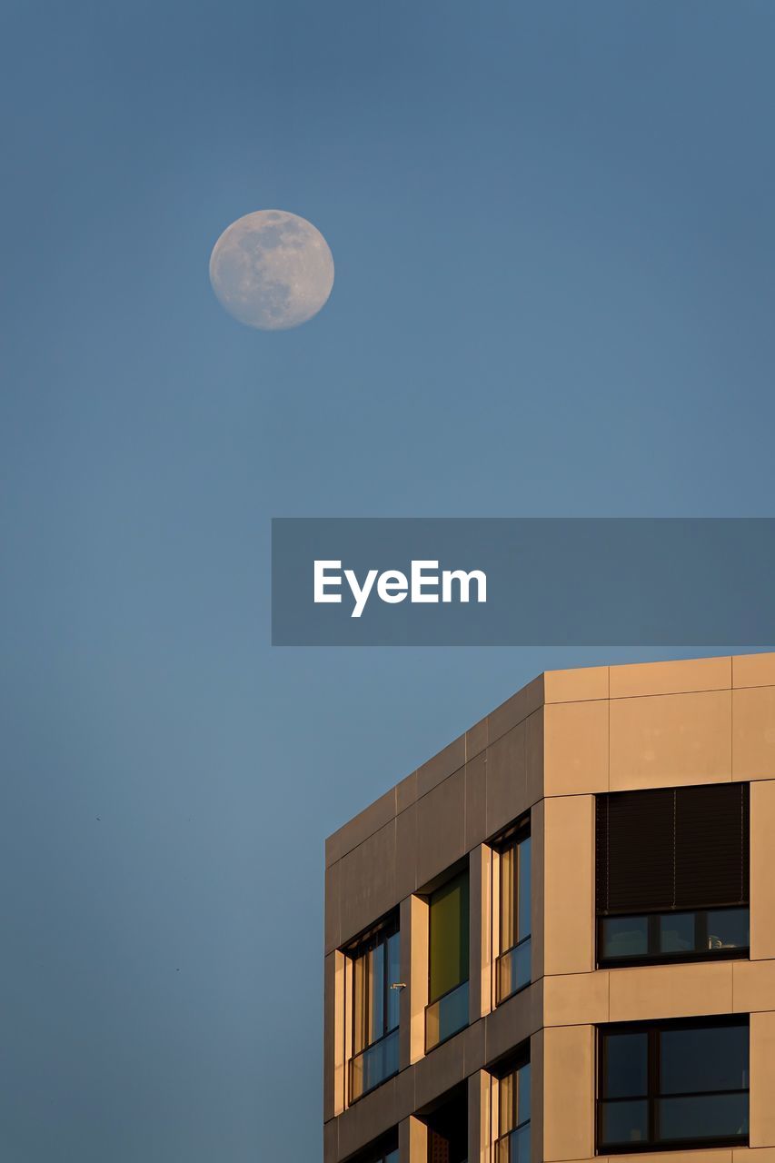 Low angle view of building against clear blue sky and moon