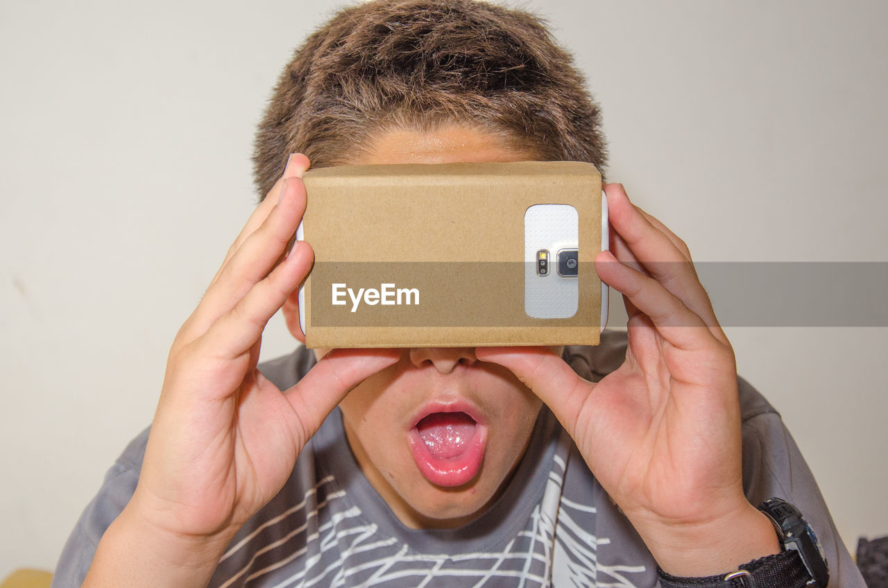 Close-up of surprised boy looking in smart phone through cardboard virtual reality simulator