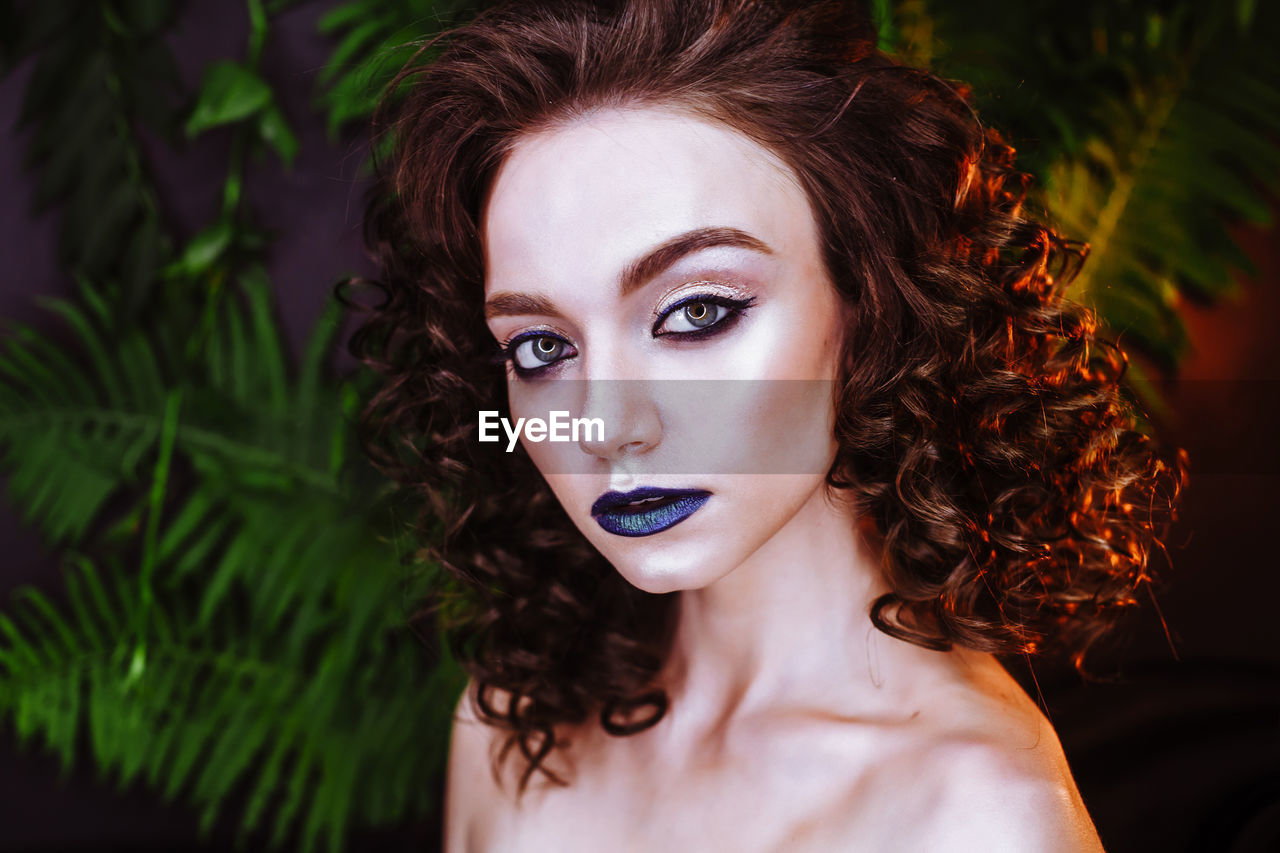 Portrait of beautiful redhead woman wearing make-up by plants