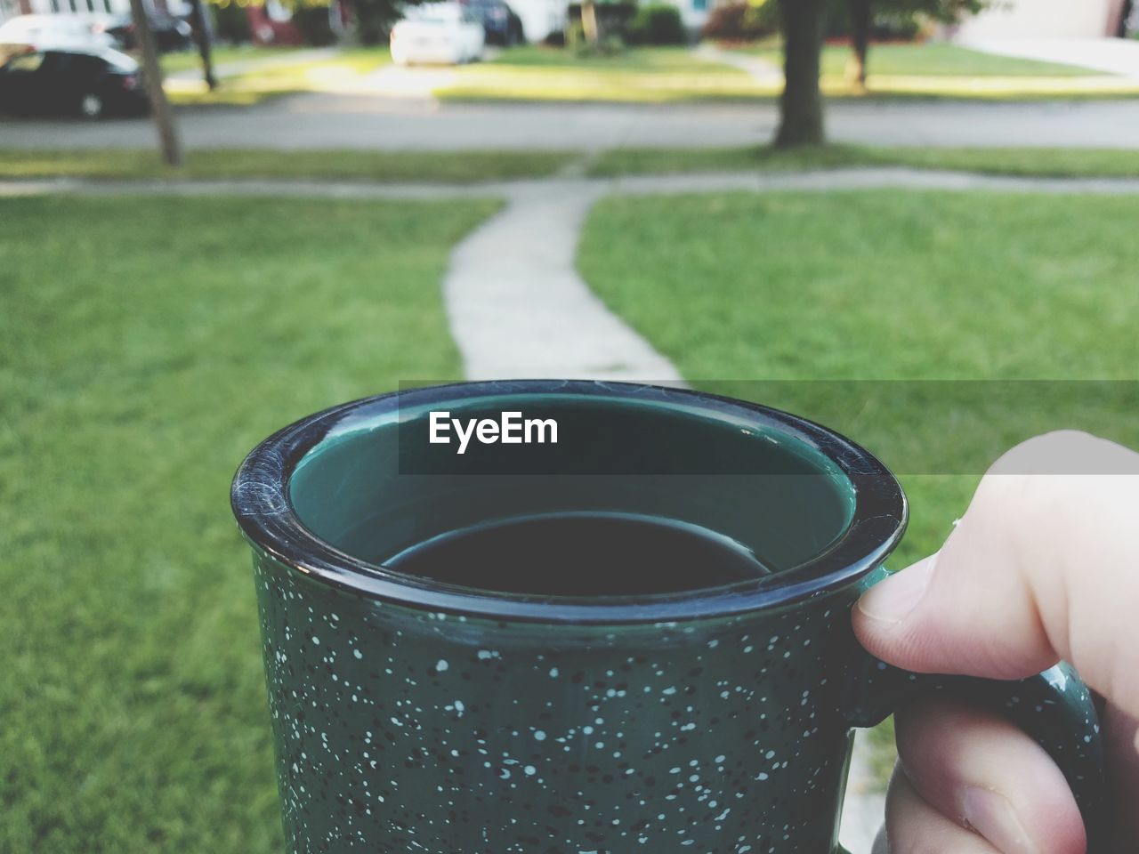 Cropped hand holding coffee cup on lawn