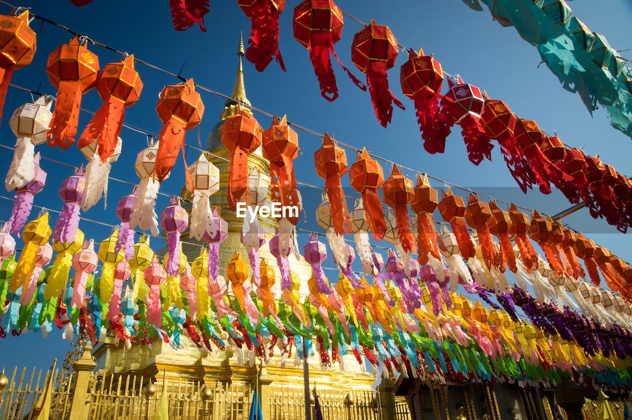 LOW ANGLE VIEW OF MULTI COLORED UMBRELLAS HANGING AGAINST SKY