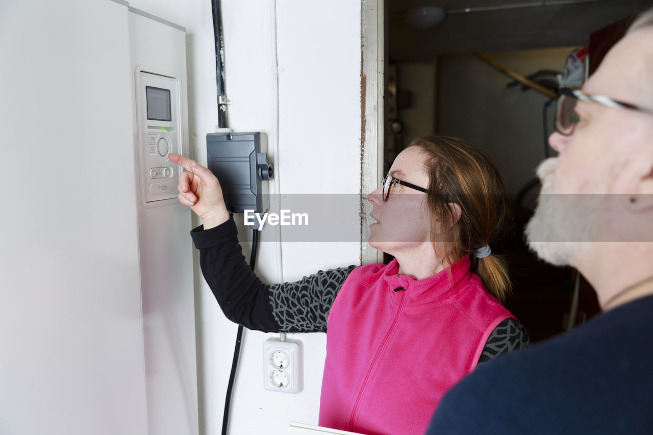 Female plumber checking boiler
