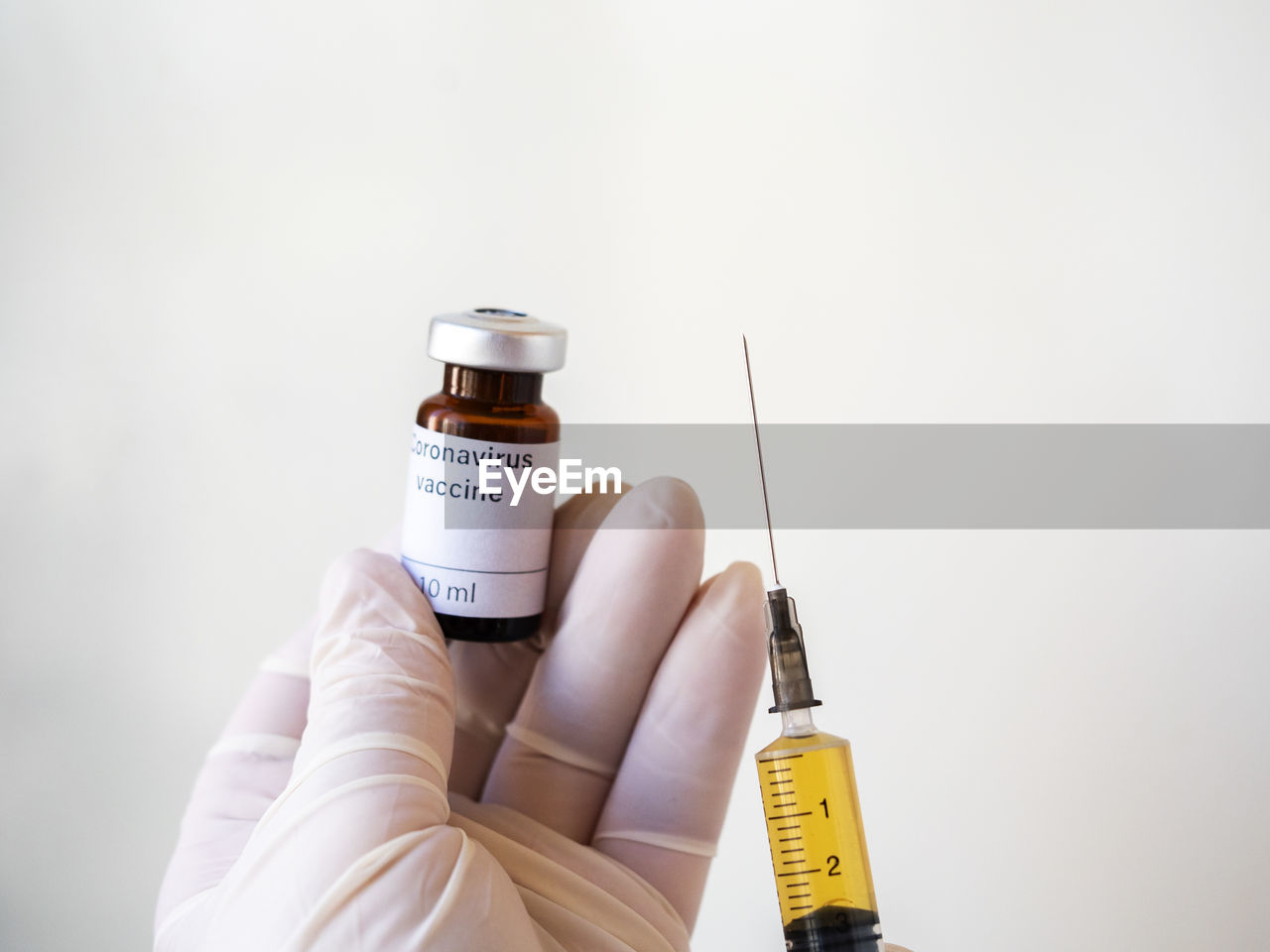 Doctor's hand holding a syringe of covid-19 vaccine and vaccine vial