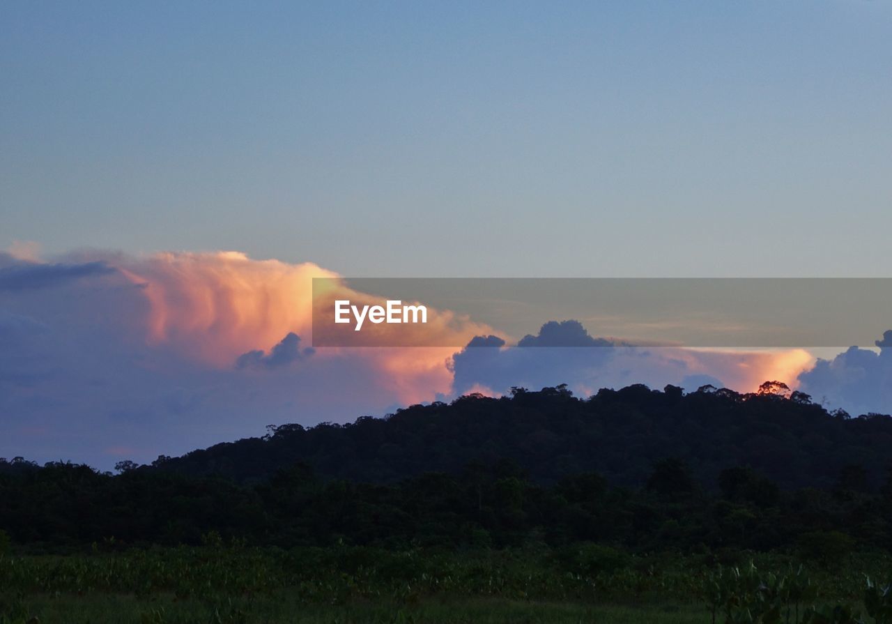 SCENIC VIEW OF SILHOUETTE FIELD AGAINST SKY AT SUNSET