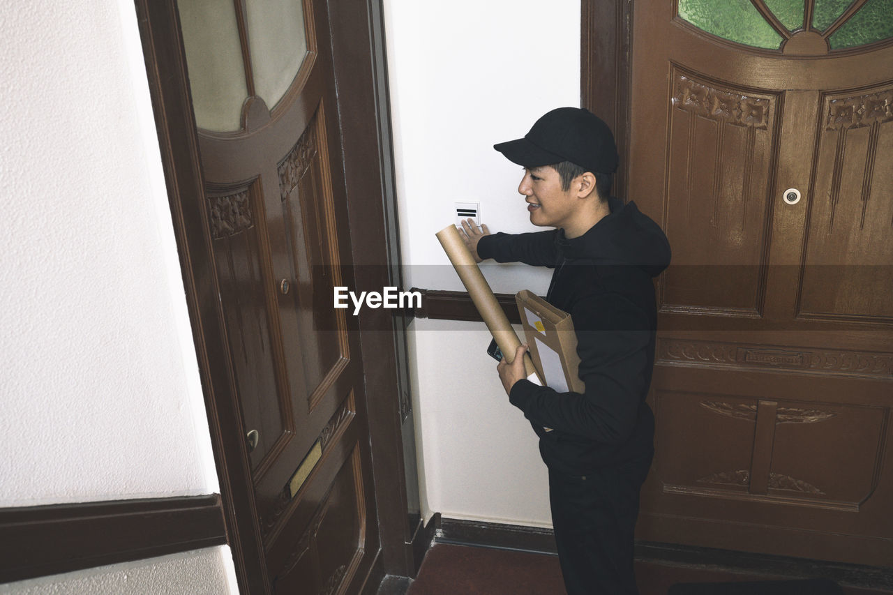 High angle view of smiling delivery man with package at doorstep