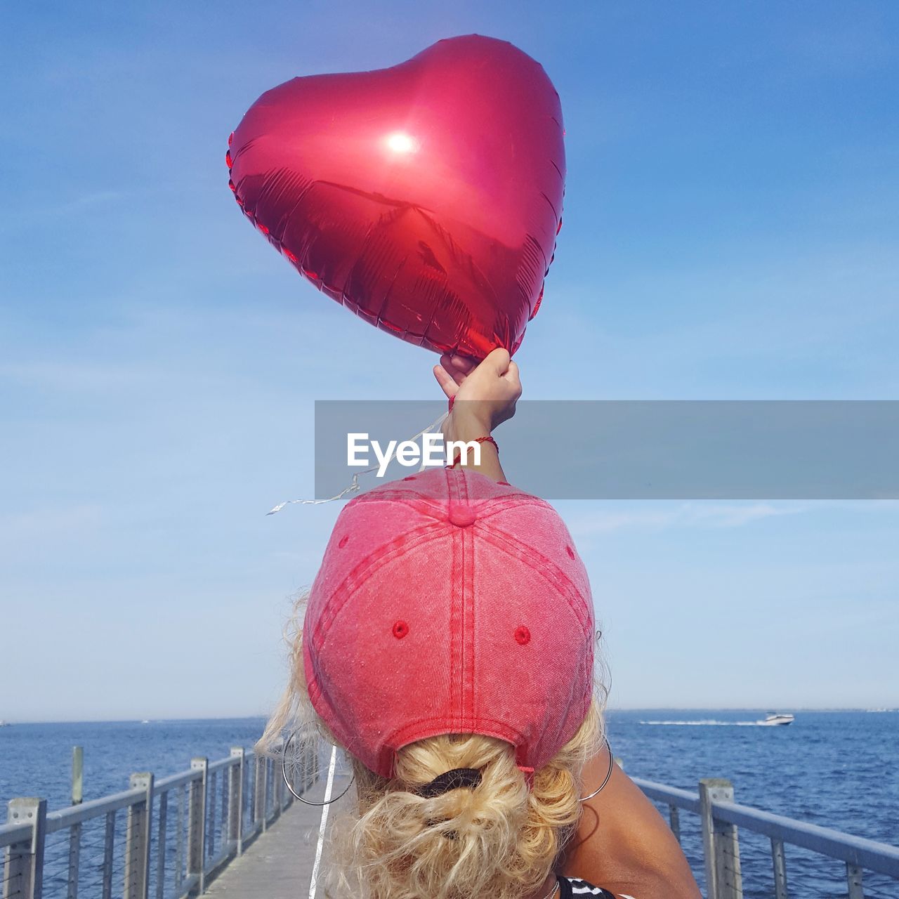 REAR VIEW OF WOMAN WITH RED UMBRELLA AGAINST SEA