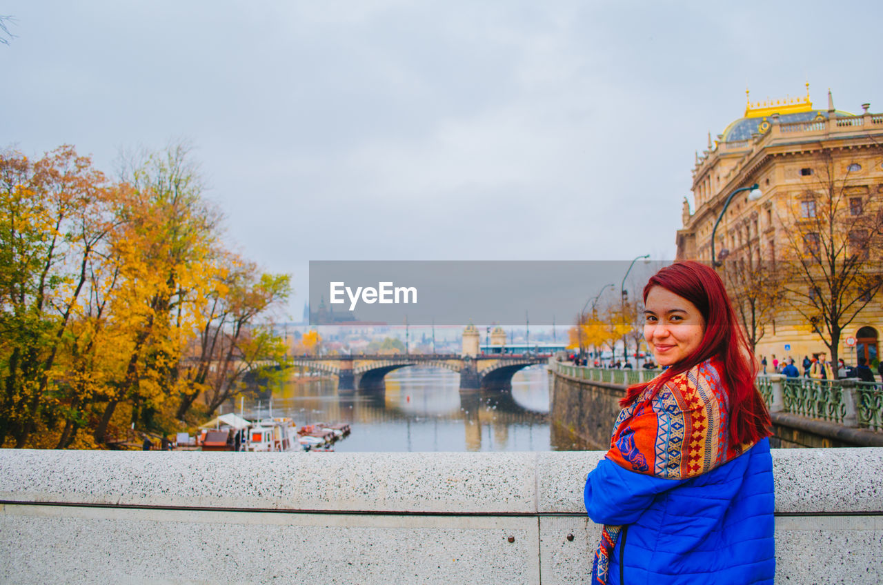 Portrait of smiling woman standing in city during autumn