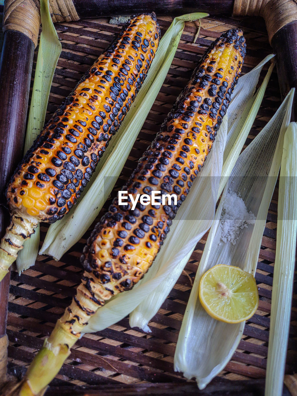 Spicy sweet corn burn in fire with lemon and salt in a wood tray from different angles