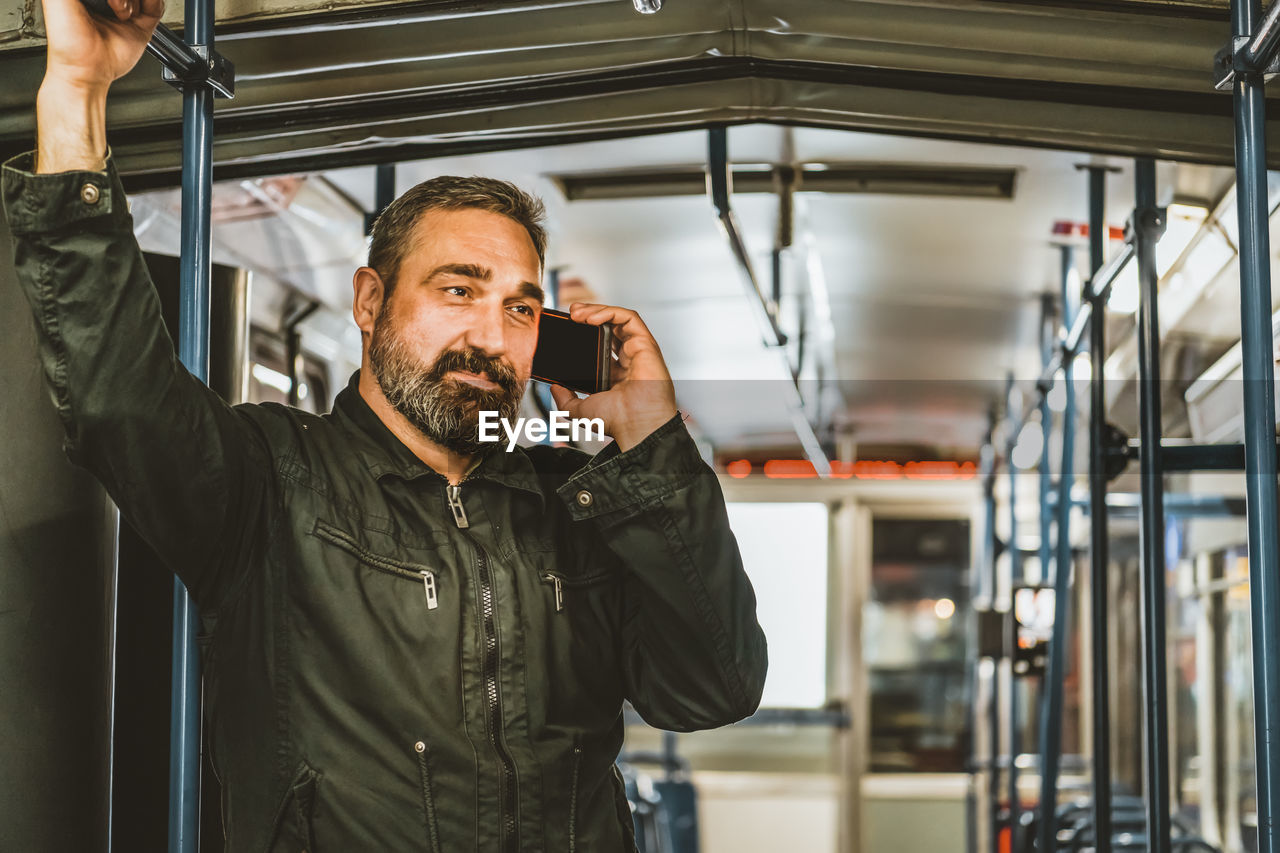 People, lifestyle, travel and public transport. attractive man talking on the phone in public bus .