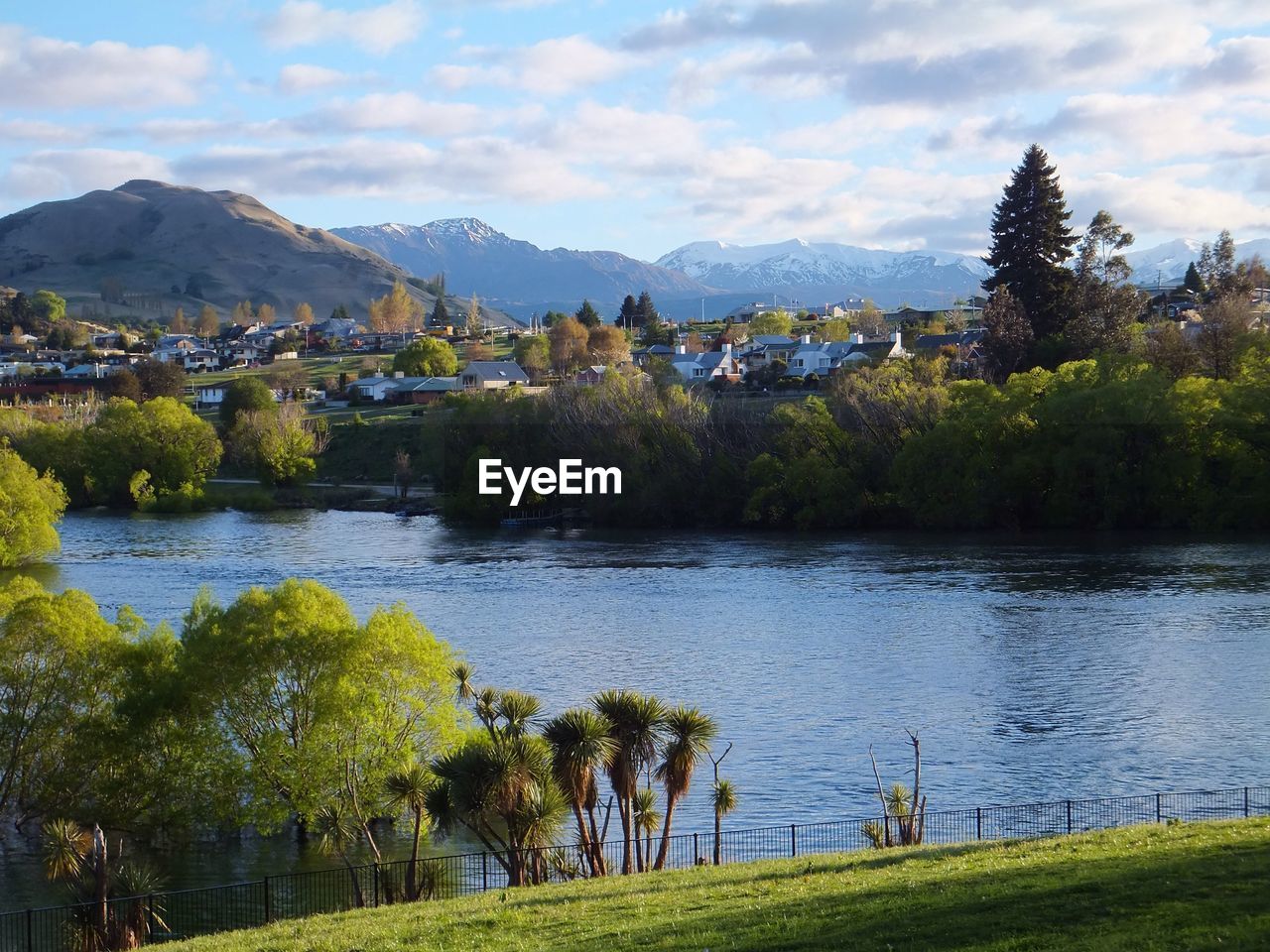 Scenic view of river and trees against mountains and cloudy sky