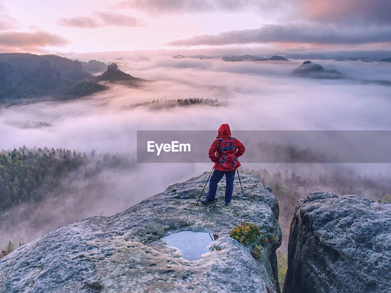 Hike with backpack and trekking sticks at edge of dangerous and popular viewpoint above deep valley