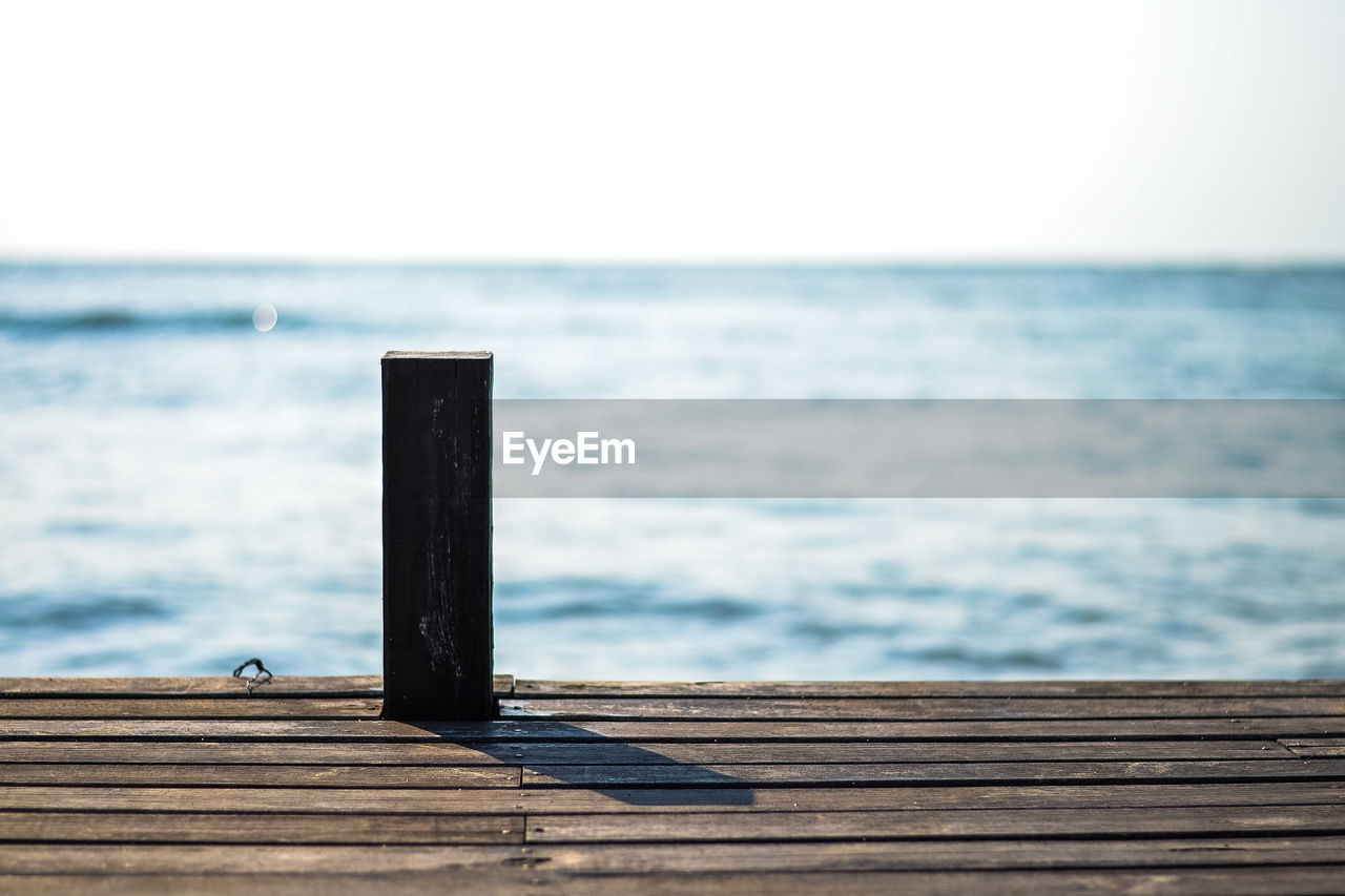 Close-up of wooden pier over sea against clear sky