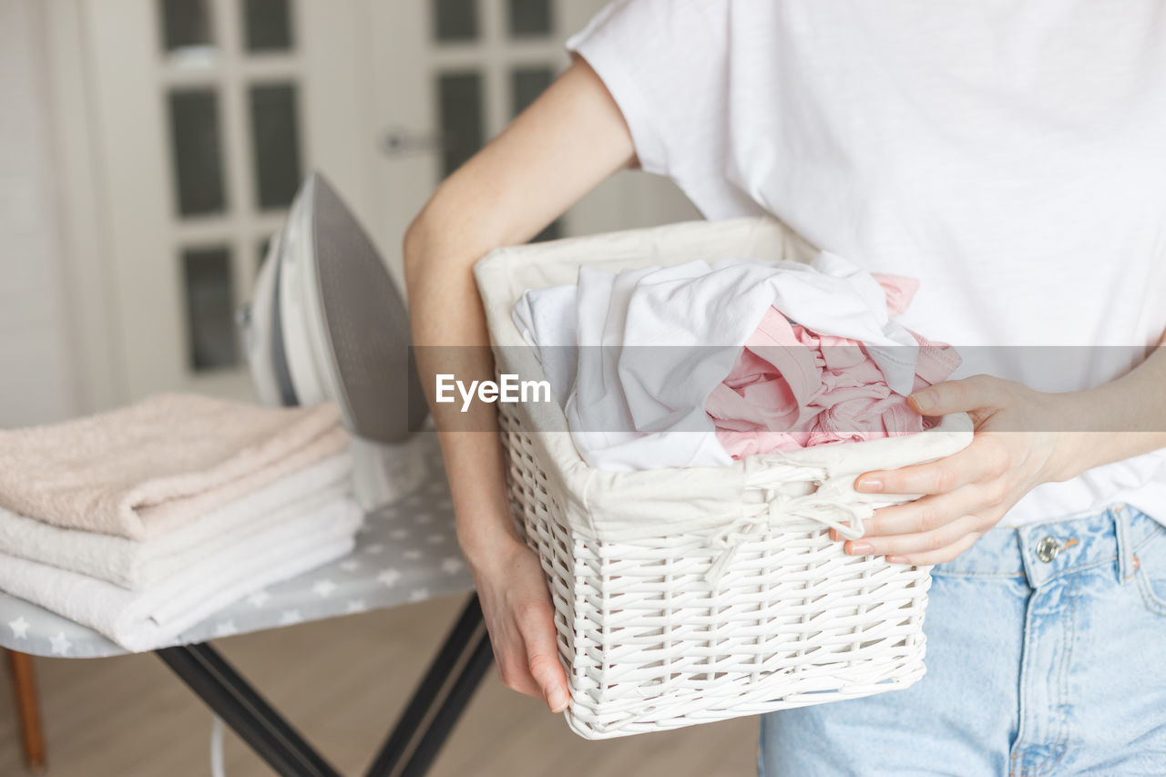 MIDSECTION OF WOMAN SITTING IN BASKET