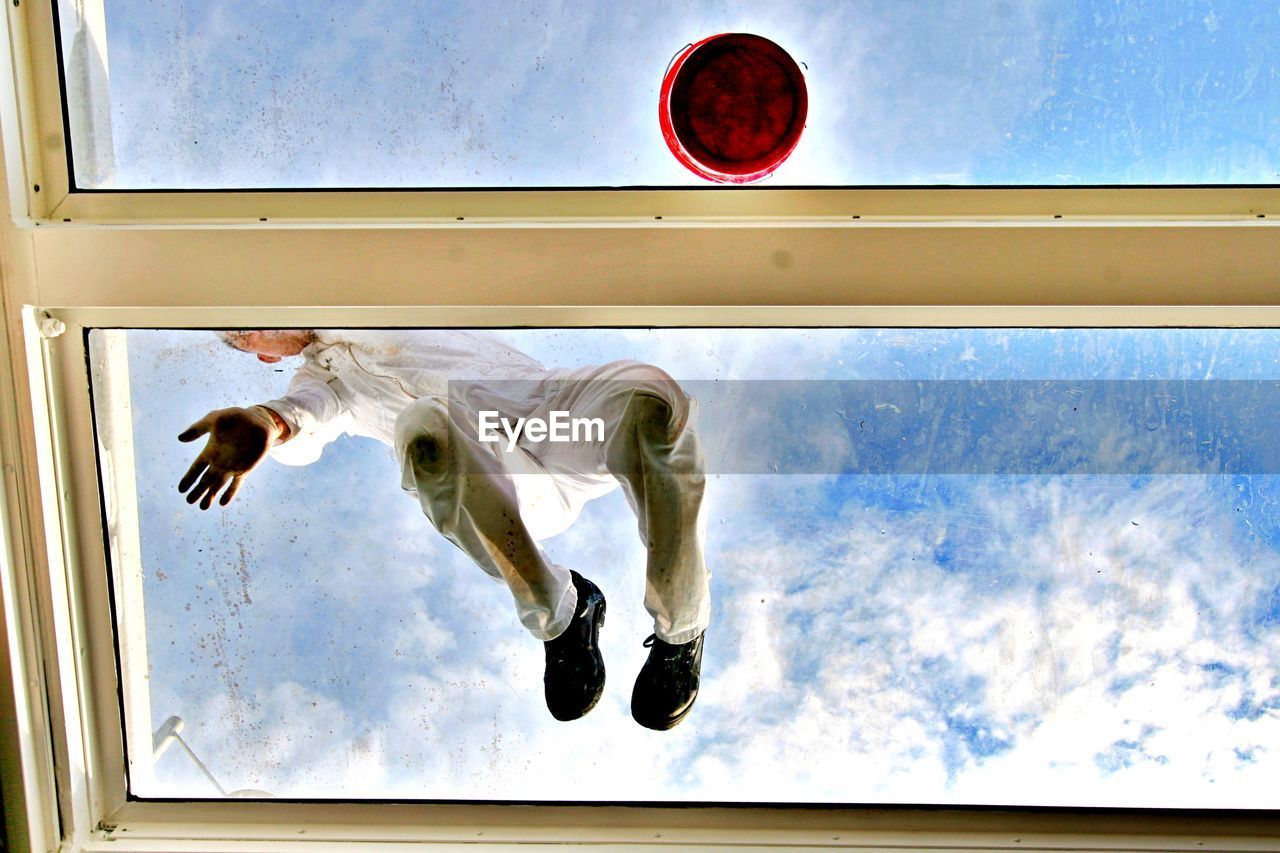 Low angle view of man on window against sky